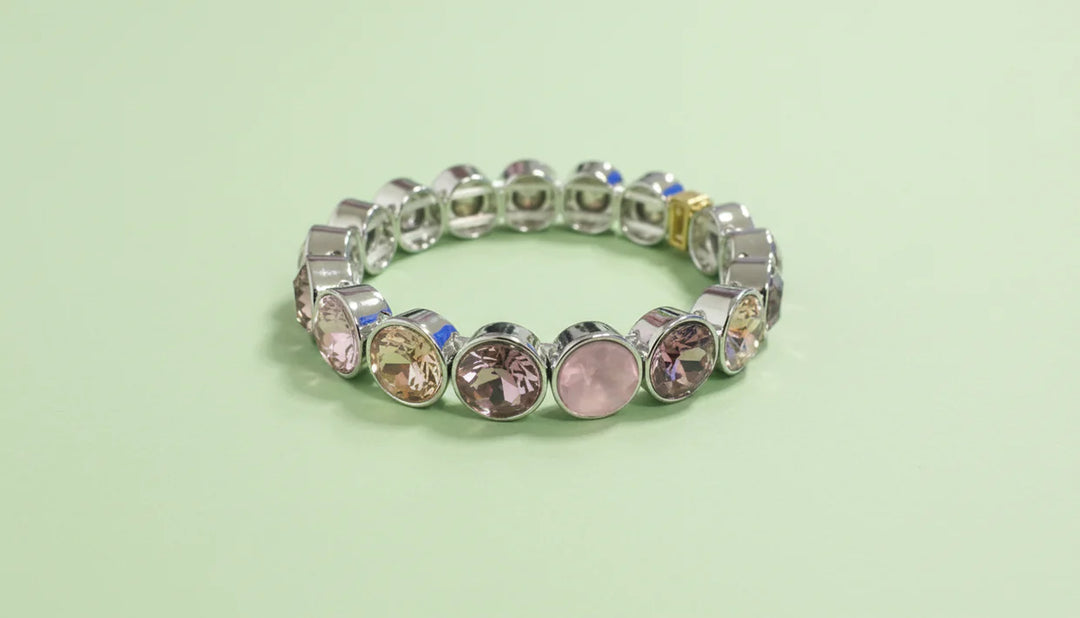 Silver bracelet with colorful gemstones on a light green background